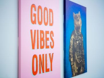 Photo of two wall canvas pictures, closest one says "Good Vibes Only"