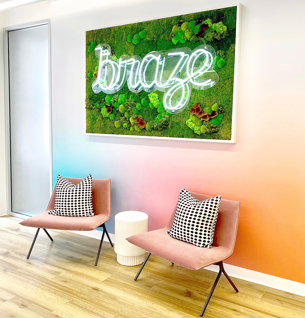 Two chairs in the office below the Braze light up sign on a multi-colored pastel wall