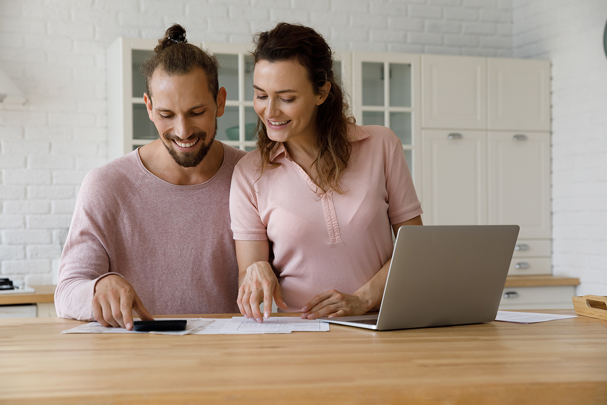 Couple using a laptop and calculating expenses