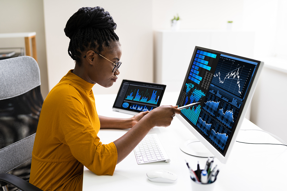 Business data analyst woman working on a computer with financial graphs on the screen