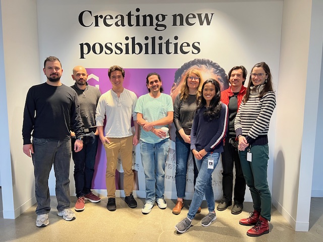 Udemy’s engineering team members stand by an office wall that reads “Creating new possibilities.”