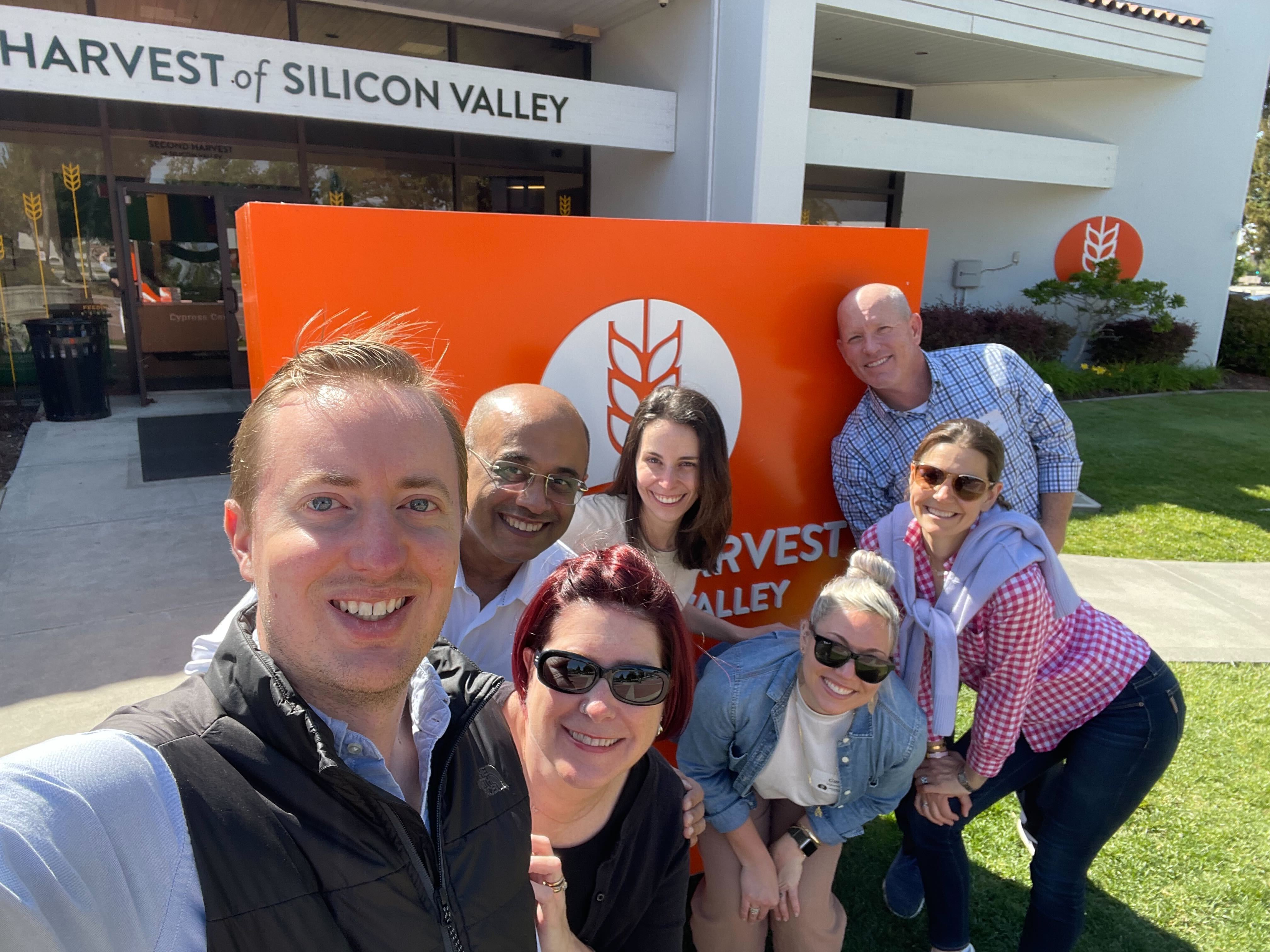 Members of Eightfold AI's team posing for a selfie in front of the sign of Second Harvest of Silicon Valley.