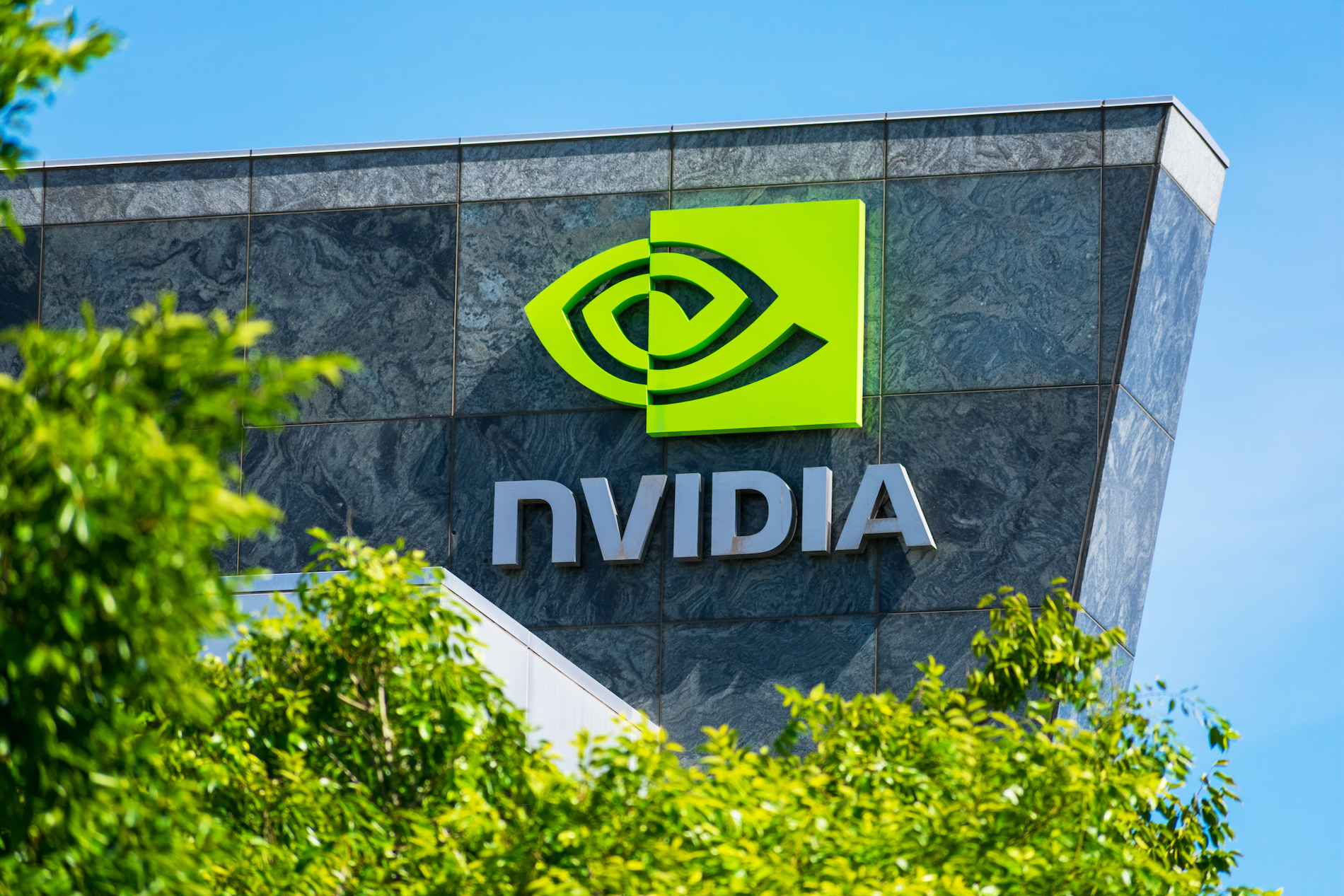 NVIDIA logo on a building with an angular shape. Trees in the foreground. 