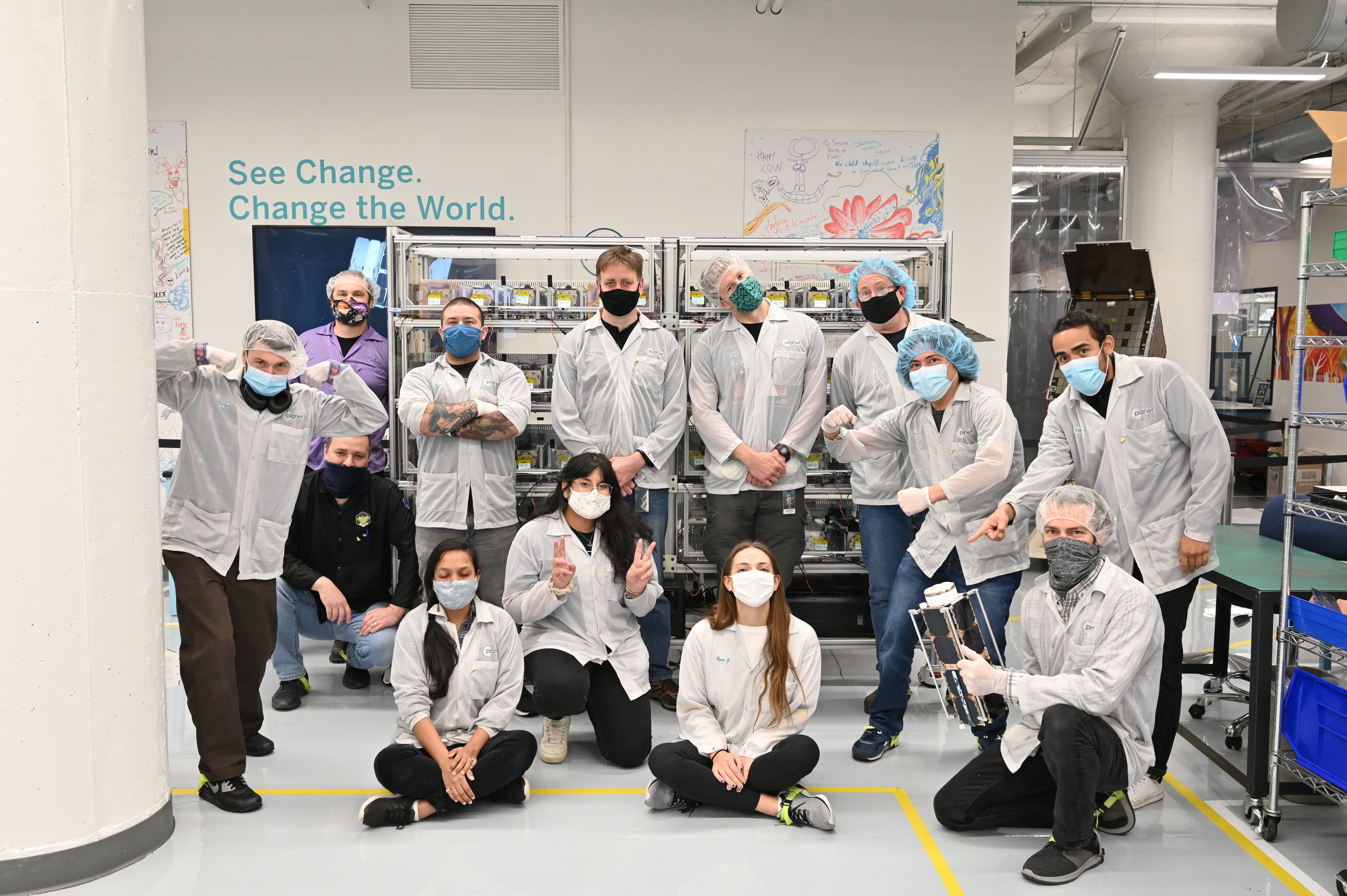 People pose in white lab coats and masks in lab