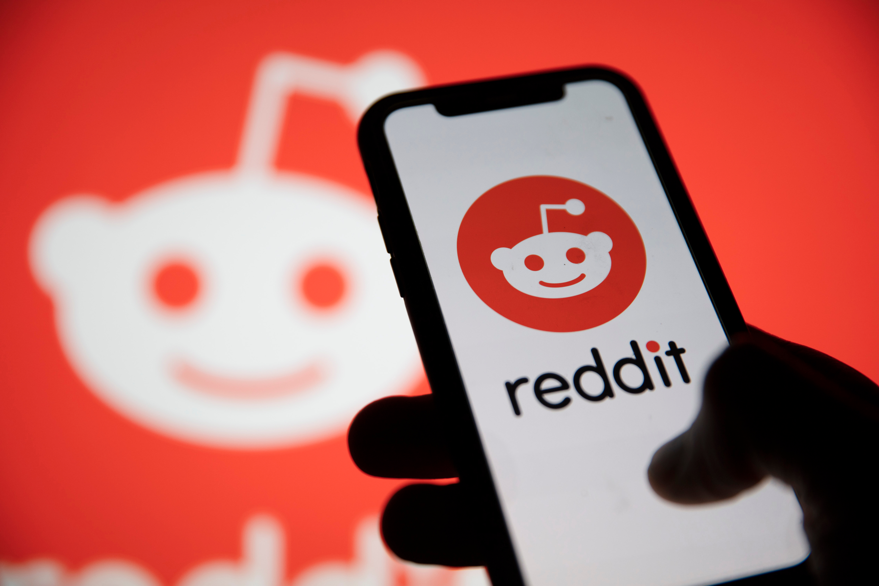 Image of Reddit on an iphone with a Reddit banner behind.