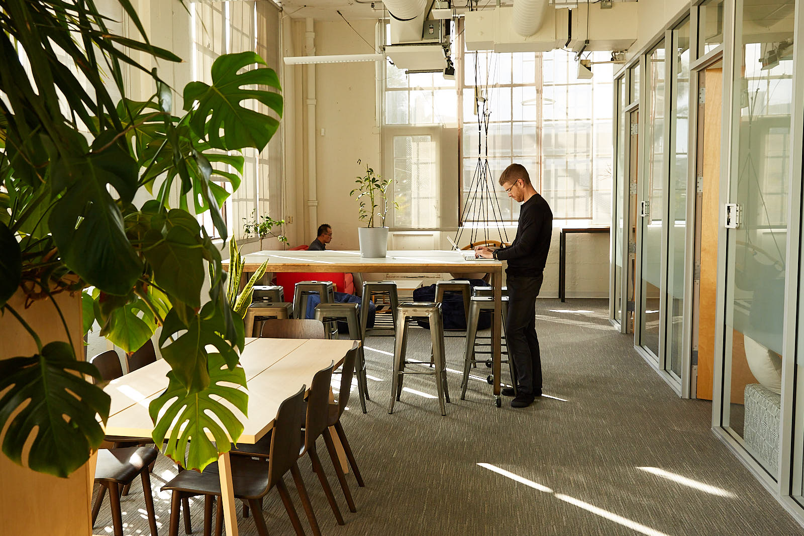 WeaveGrid's coworking space with rectangular tables and two people working on laptops