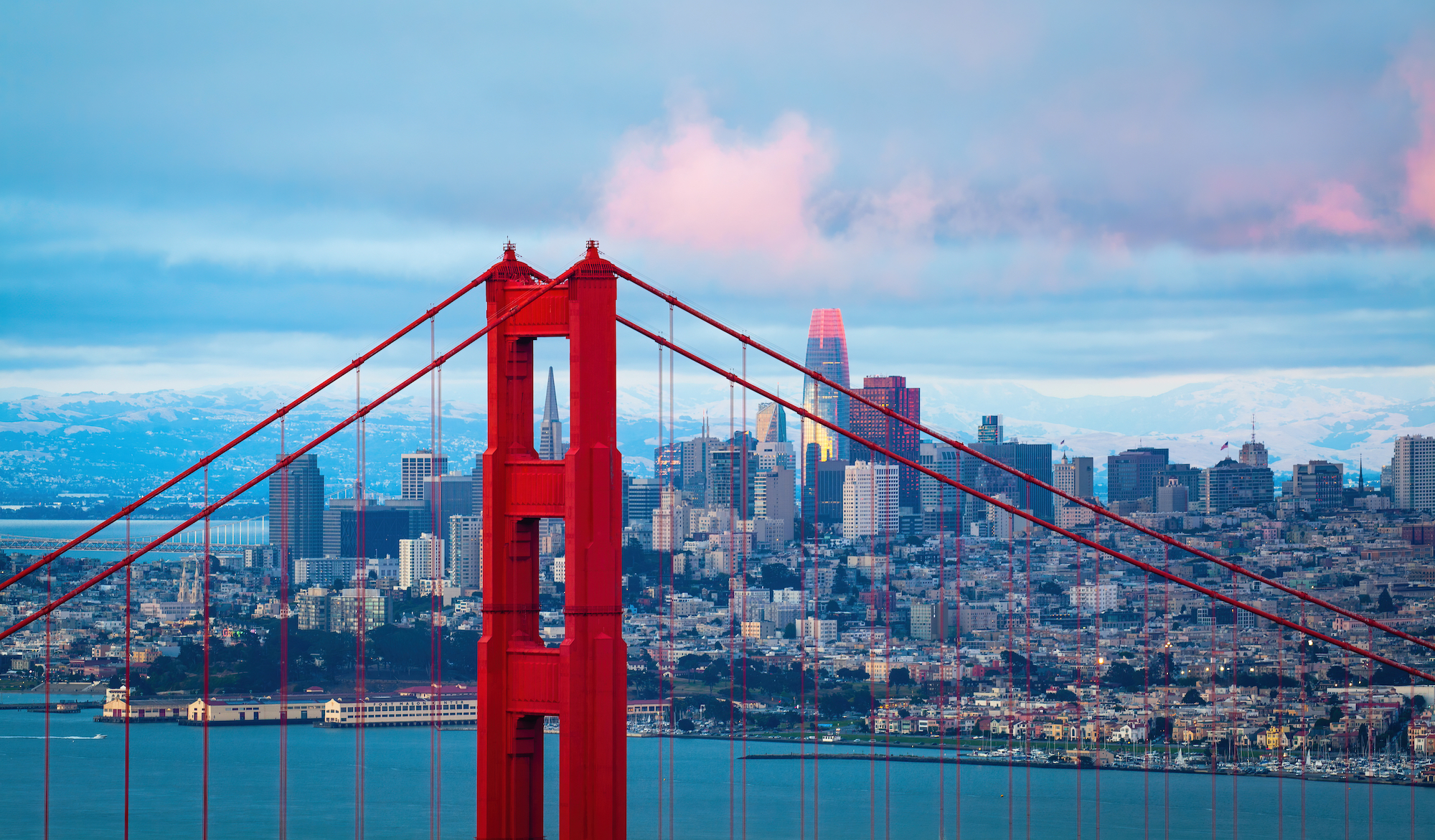 The golden gate bridge is pictured in front of the SF skyline.