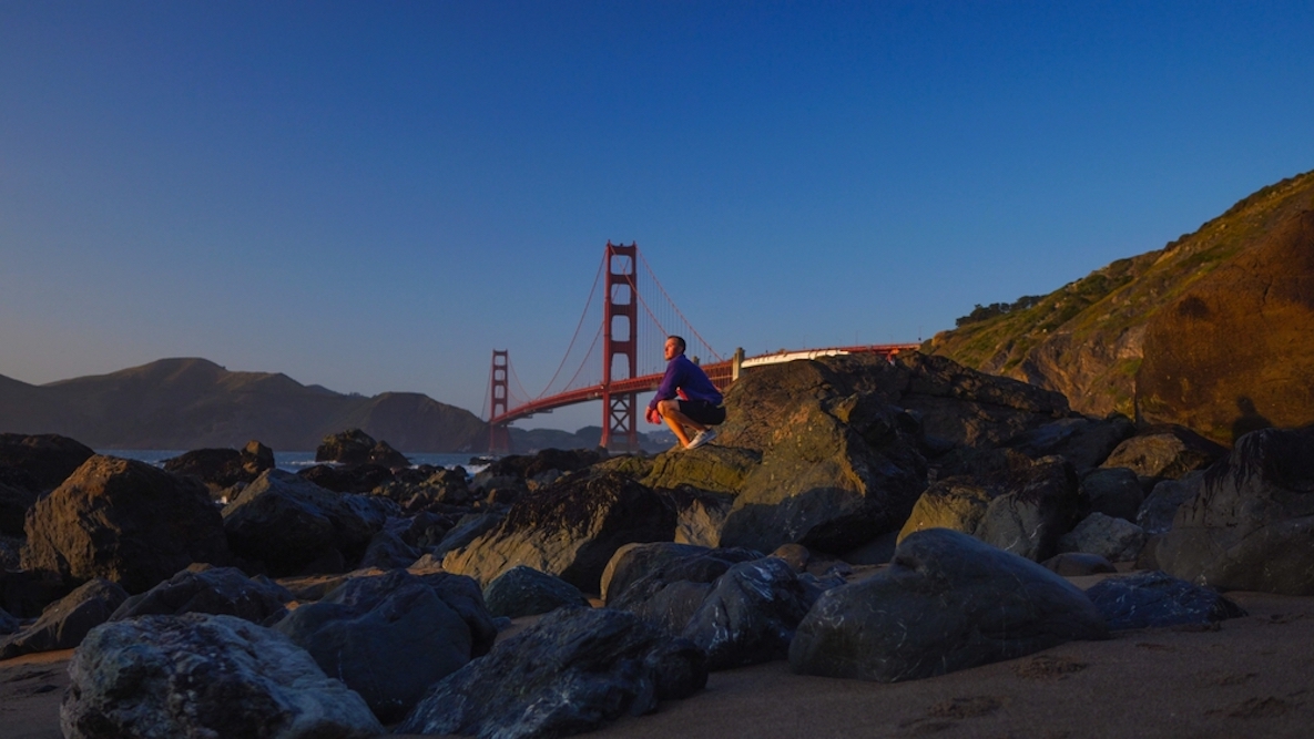 Someone standing on a mountain with the Golden Gate bridge in the background