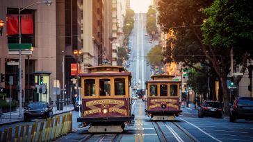 Two trolleys travel through the downtown San Francisco area.