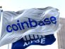 A flag bearing the Coinbase logo flys in front of a flag bearing the logo of the New York Stock Exchange